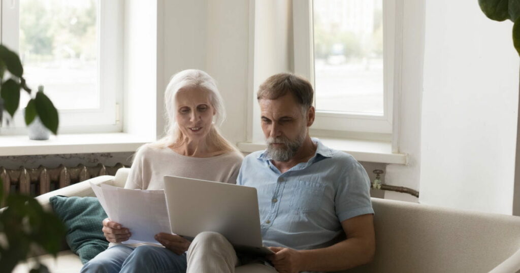 Focused retired mature couple reviewing living will online documents together, visit TrustHandled to learn more.